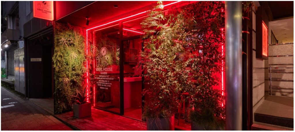 ภายนอกร้านที่โดดเด่นด้วยต้นไม้และแสงนีออนสีแดง